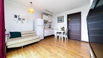 A compact living space with a sofa, dining table, and kitchen area.