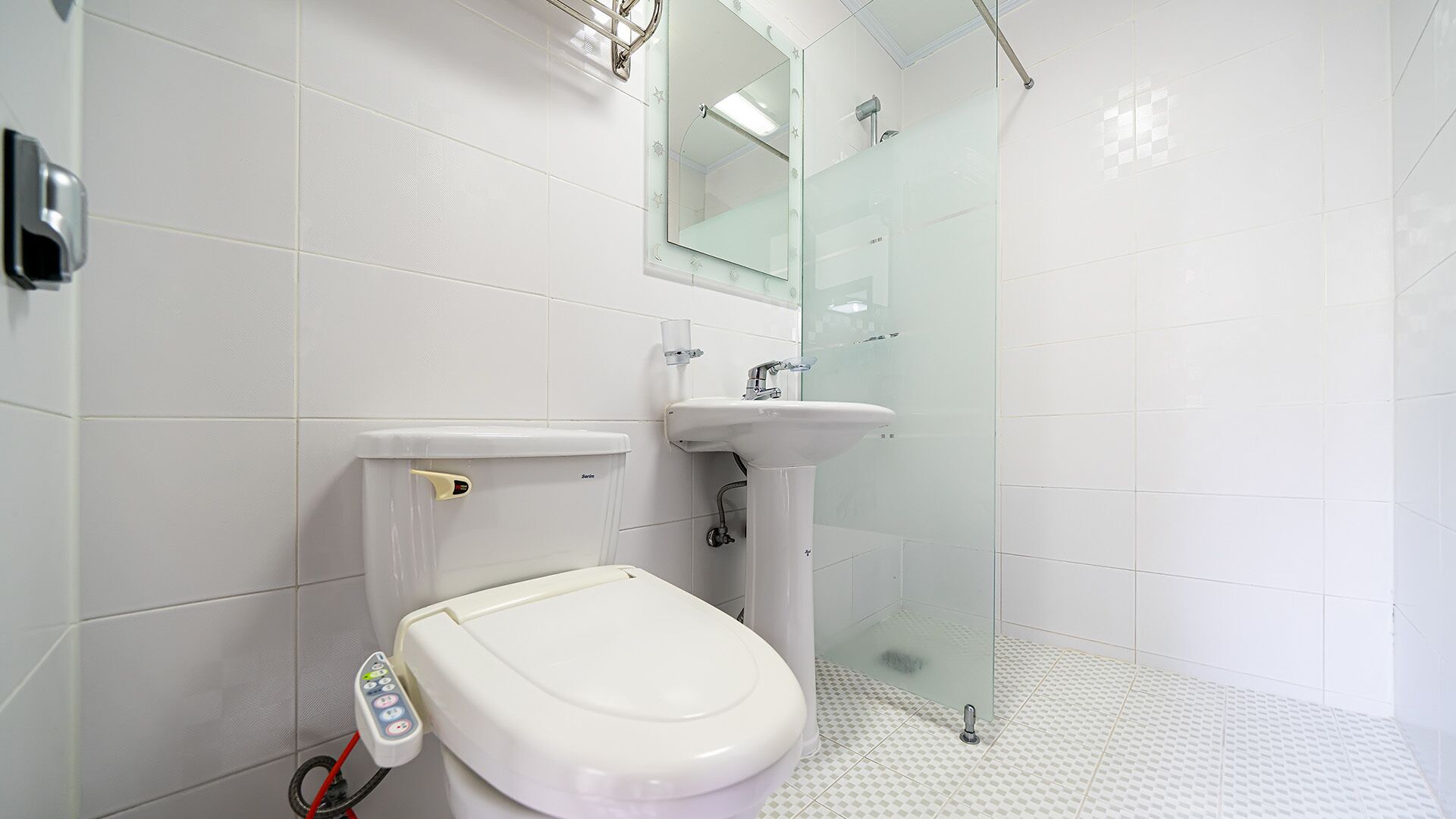 Ein modernes Badezimmer mit Toilette, Waschbecken und einer Duschkabine aus Glas.
