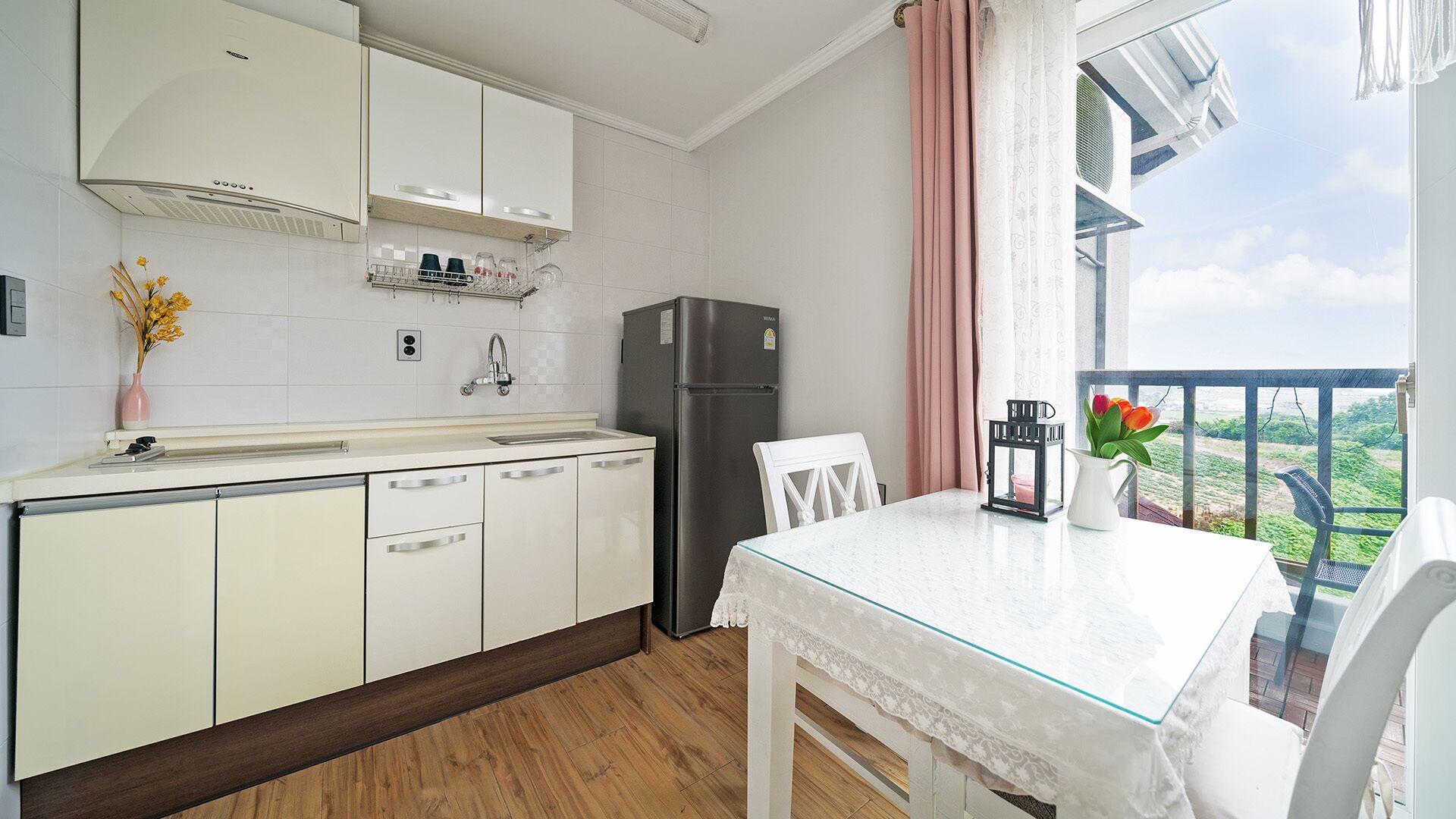 A modern kitchen with white cabinets, a stainless steel refrigerator, and a dining area with a glass table.