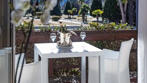 Eine Terrasse mit einem weißen Tisch und Stühlen, einer Champagnerflasche und einem Weinglas.