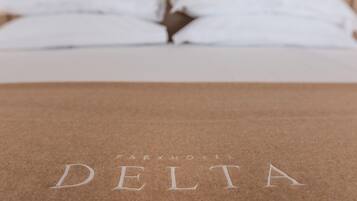 Una cama con ropa blanca y una cubierta marrón con el bordado 'PARKHOTEL DELTA'.