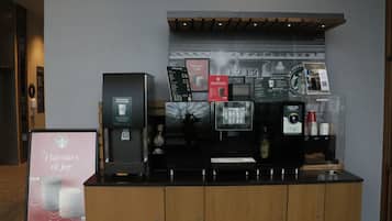 A coffee station with a menu board, a coffee machine, and a Starbucks cup display.