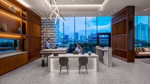A modern hotel lobby with a reception desk, seating area, and large windows offering a city view. - Citadines Rochor Singapore (Singapore)