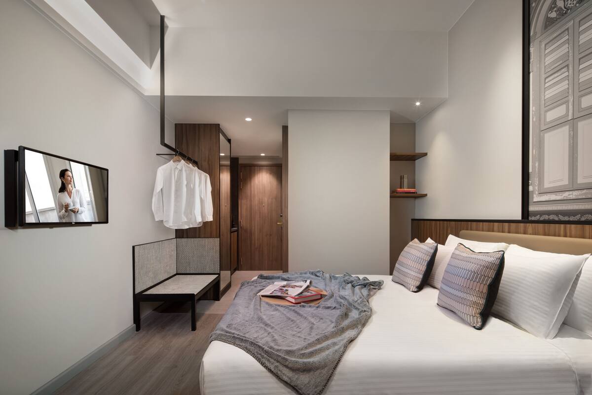A modern bedroom with a bed, a bedside table, a mirror, and a wardrobe.