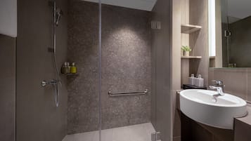 A modern bathroom with a glass shower enclosure, a white sink, and a mirror above it.