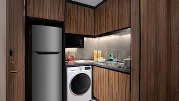 A compact kitchen with wooden cabinets, a built-in washing machine, a microwave, and a sink.