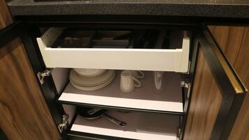 Un cajón de cocina con utensilios y platos.