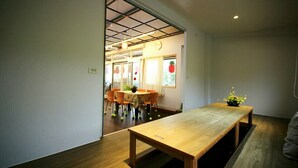 A modern interior with a wooden table and chairs, a dining area in the background, and a ceiling with a grid pattern. - Coffee Street Homestay (Gukeng)