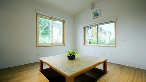 A room with a wooden table, two windows, and a small plant on the table. - Coffee Street Homestay (Gukeng)