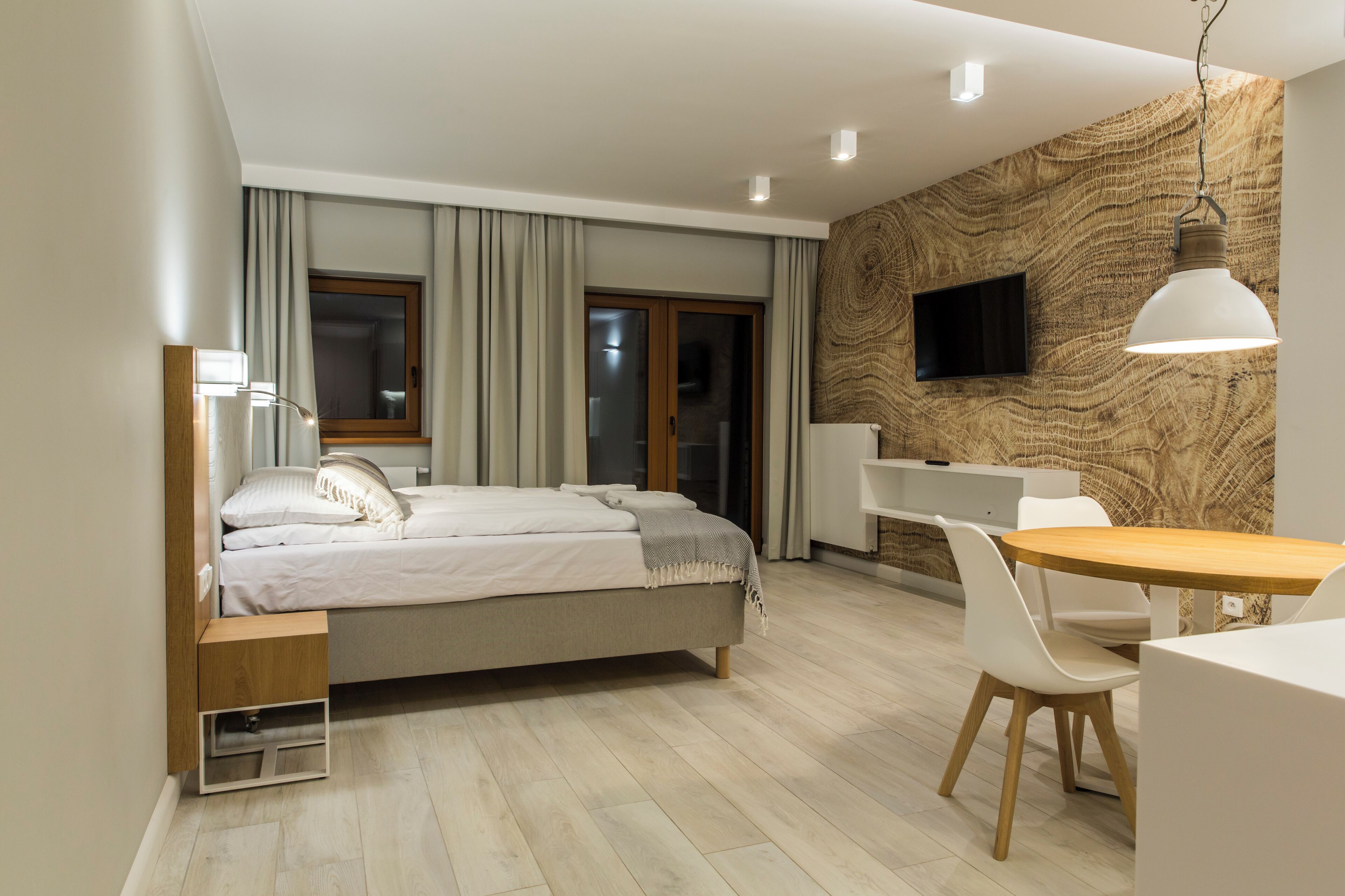 A modern bedroom with a bed, bedside table, and a desk area with a chair.