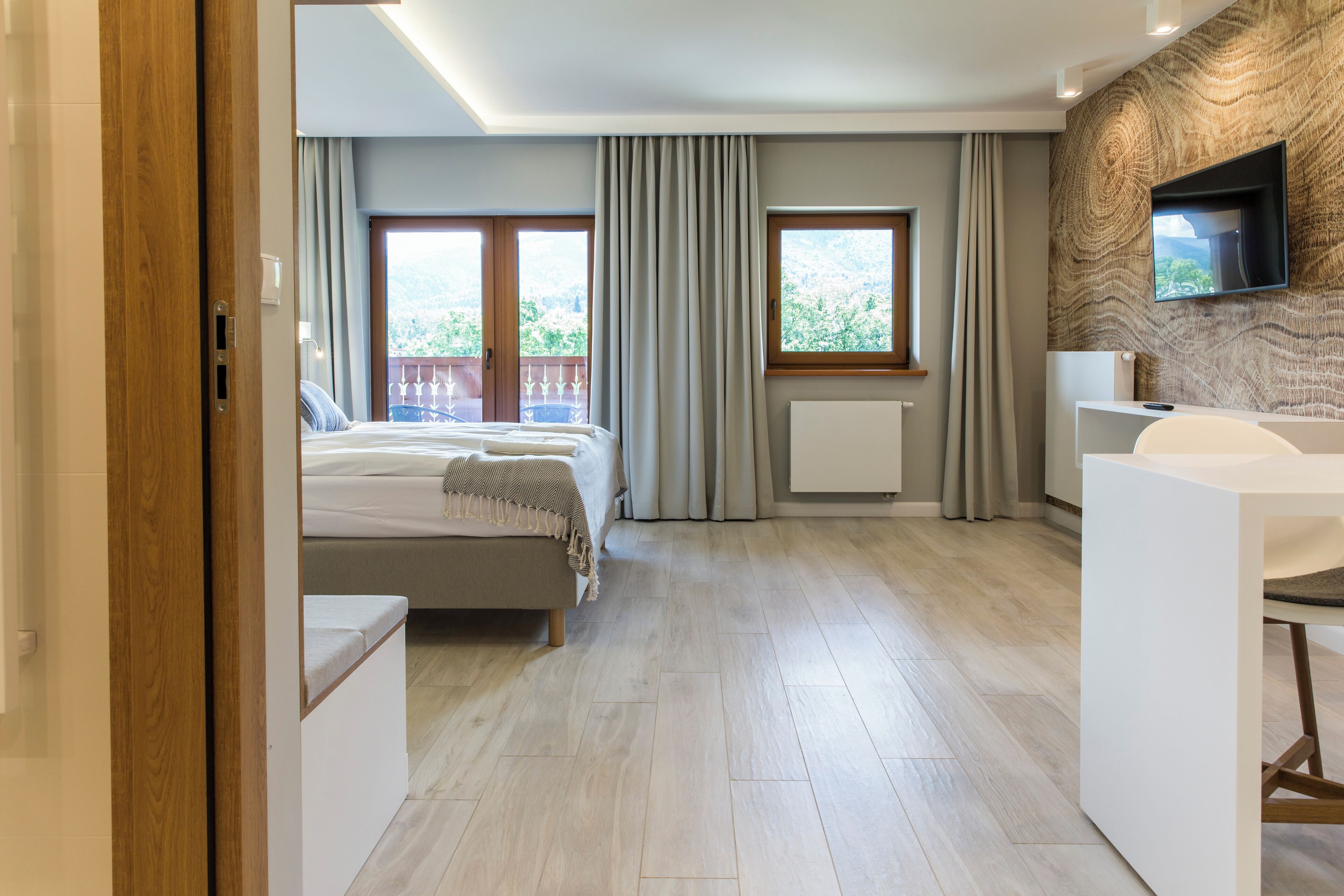 Una habitación de hotel moderna con una cama, un escritorio y un televisor montado en la pared.