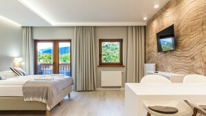 A modern hotel room with a bed, a desk, and a TV mounted on the wall. - Royal Hill Residence (Zakopane)