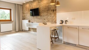 A modern kitchen with a built-in island, a flat-screen TV, and a window with curtains. - Royal Hill Residence (Zakopane)