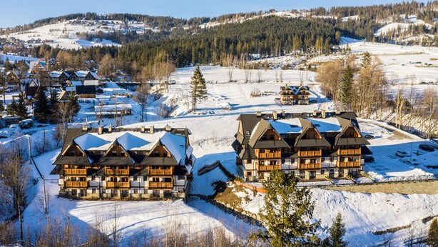 A snow-covered lodge with multiple balconies and a ski slope in the background. - Royal Hill Residence (Zakopane)