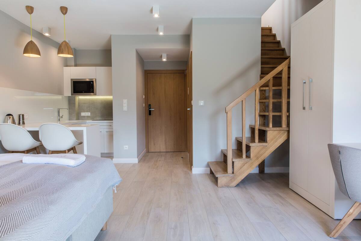 Un appartamento moderno con cucina, zona pranzo, camera da letto e una scala.