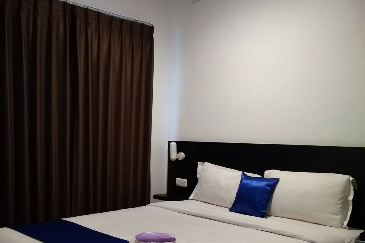 A hotel room with a bed, curtains, a headboard, and a pillow.