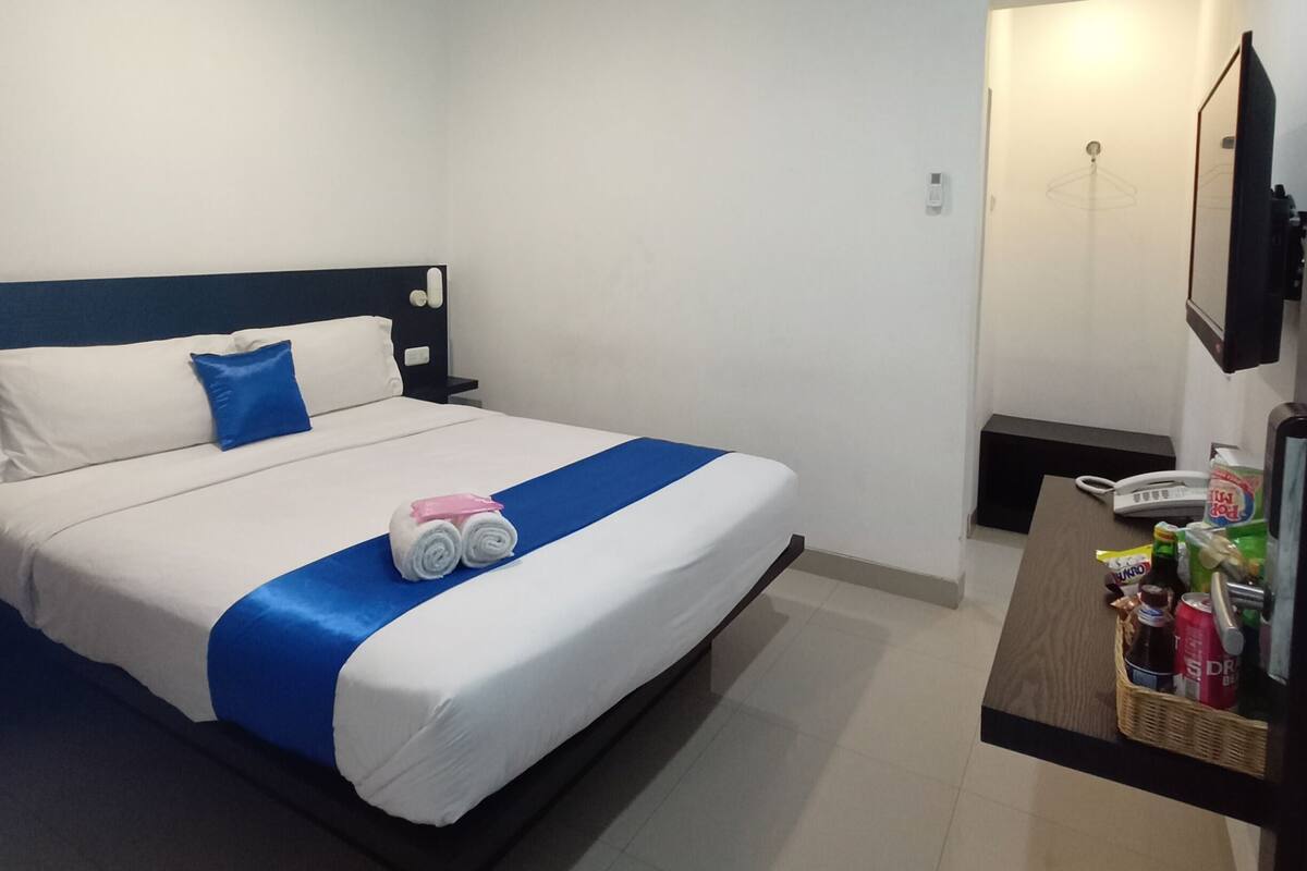 A hotel room with a bed, a desk, and a mirror.