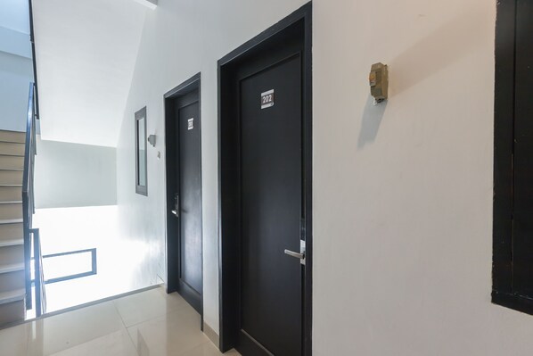 A corridor with black doors, one marked with the number 202, and a small mailbox on the wall. - Puri Maju (Jakarta)