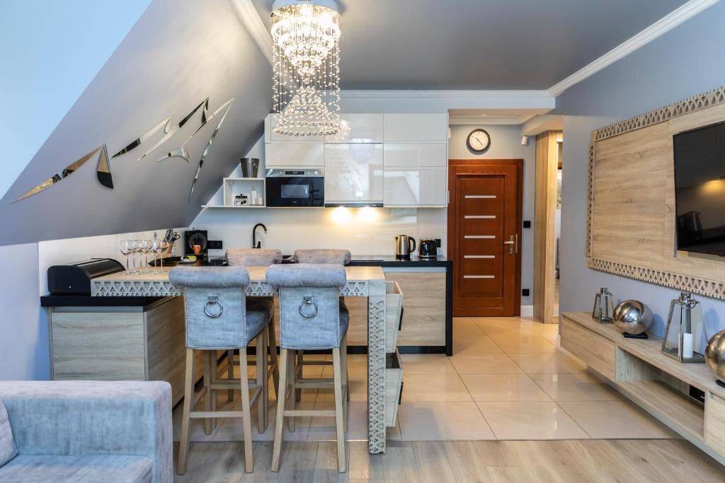 A modern kitchen with a bar area, a wooden door, and a large TV on the wall.
