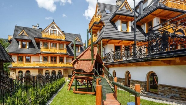 A multi-story building with balconies, a wooden staircase, and a garden area.