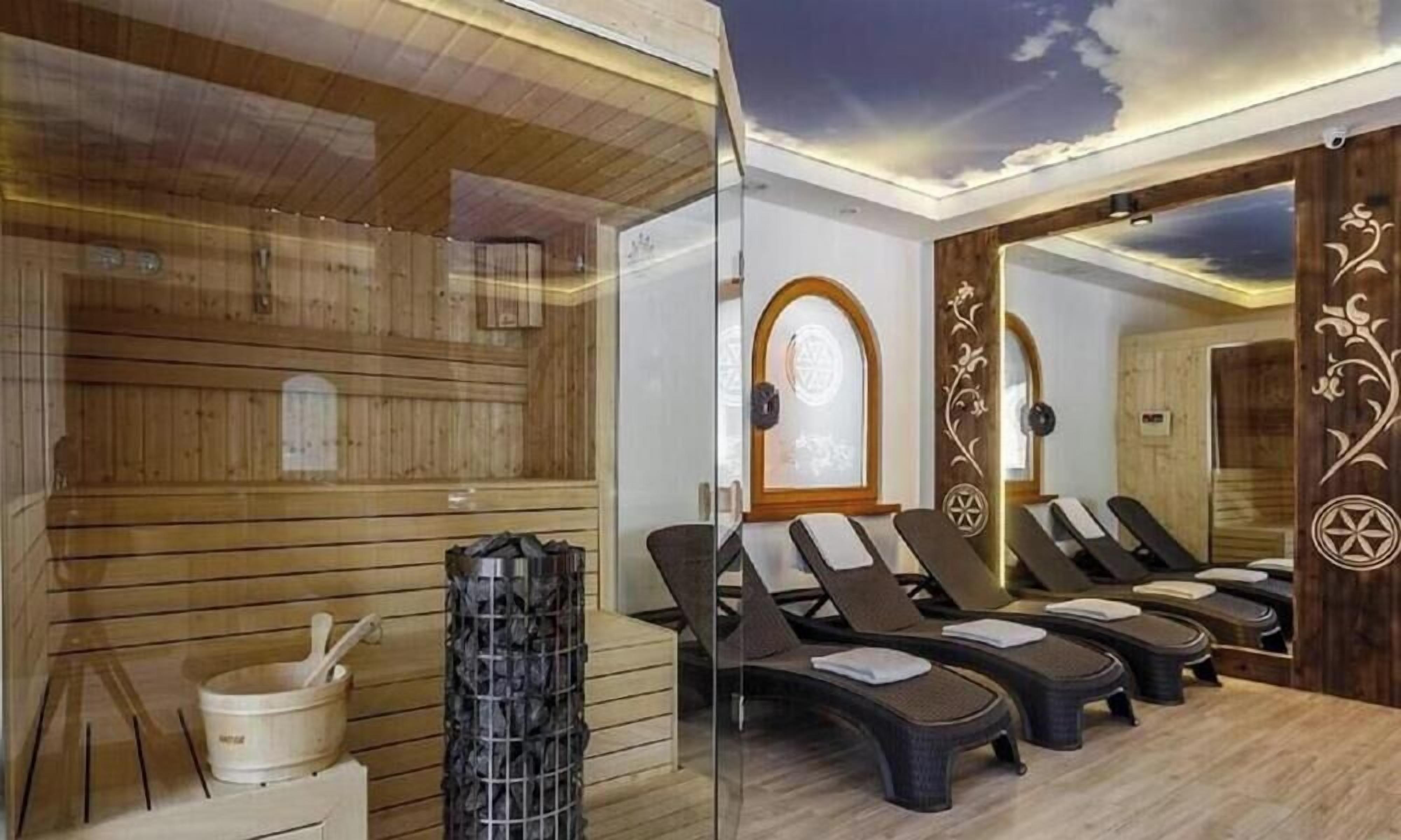 Ein Sauna-Raum mit Holzwänden, einer Glastrennwand und mehreren Liegestühlen.