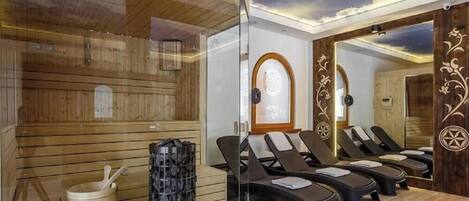 Ein Sauna-Raum mit Holzwänden, einer Glastrennwand und mehreren Liegestühlen.