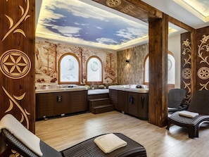 A spa room with a wooden ceiling, a mural wall, and a seating area.