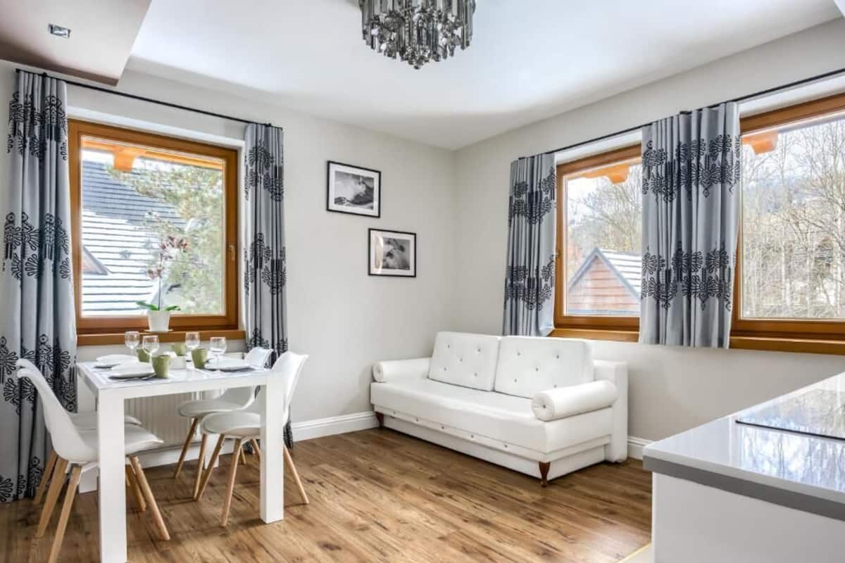A modern room with a dining table, white sofa, and large windows.