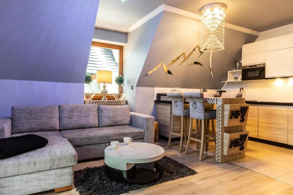 A modern living room with a sofa, coffee table, and bar area with stools.
