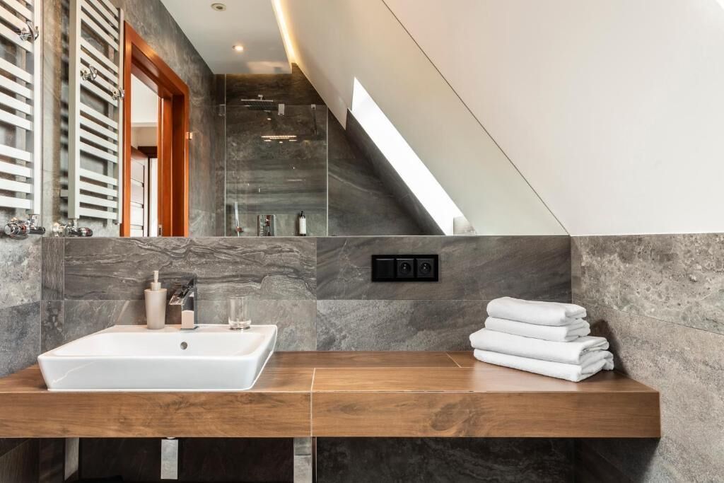A modern bathroom with a rectangular sink, a wooden countertop, and a stack of white towels.