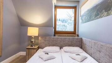 A bedroom with a bed, a nightstand, a lamp, and a window with a view of trees.