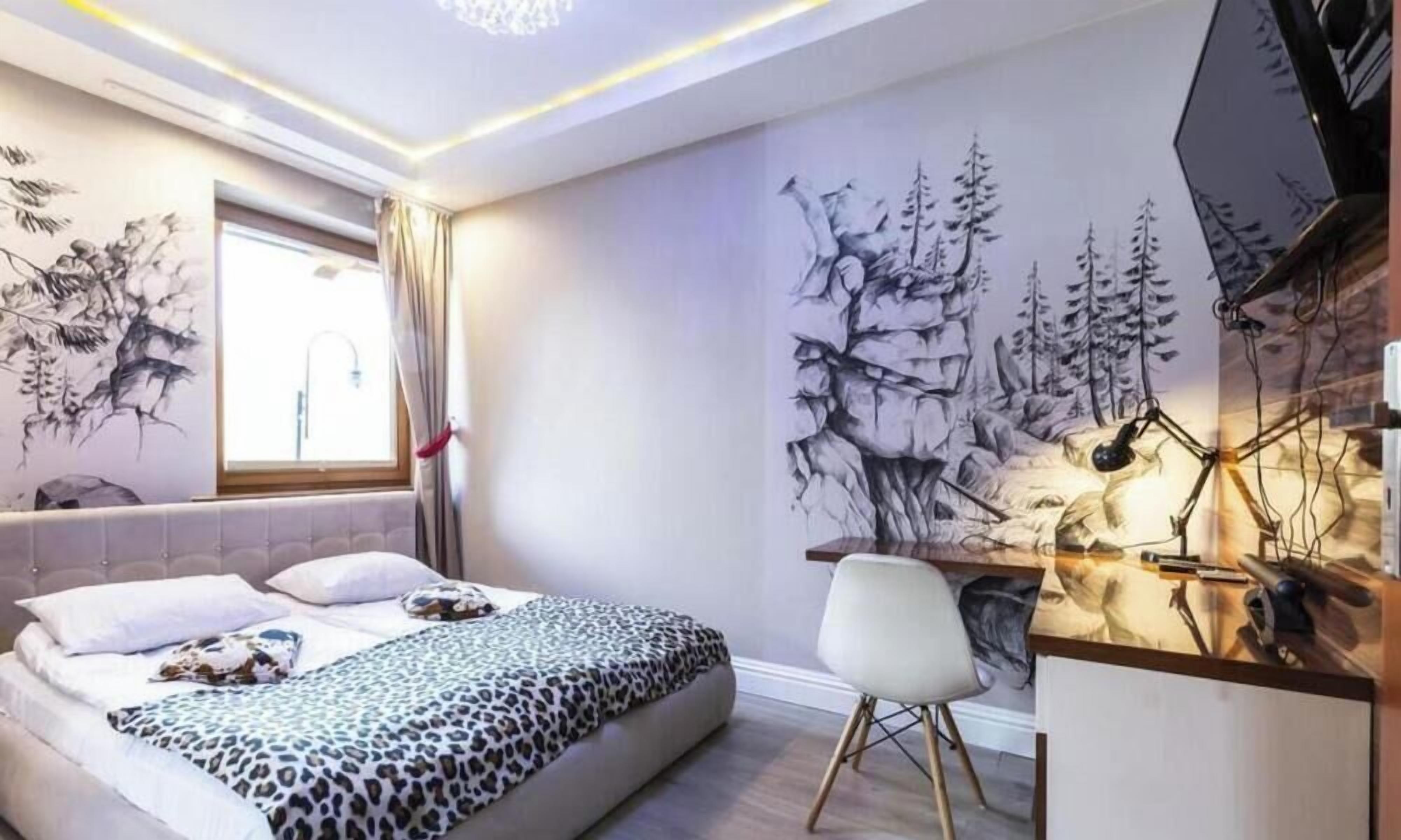 Ein modernes Schlafzimmer mit Bett, Schreibtisch und Stuhl, mit einem großen Wandbild und einem Fenster mit Vorhängen.