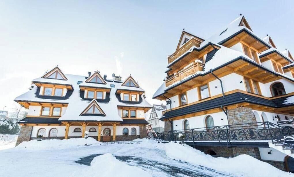 A large, multi-story building with a symmetrical facade, multiple windows, and a snow-covered roof.