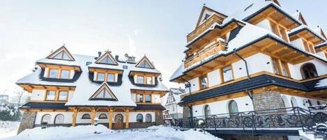 A large, multi-story building with a symmetrical facade, multiple windows, and a snow-covered roof.