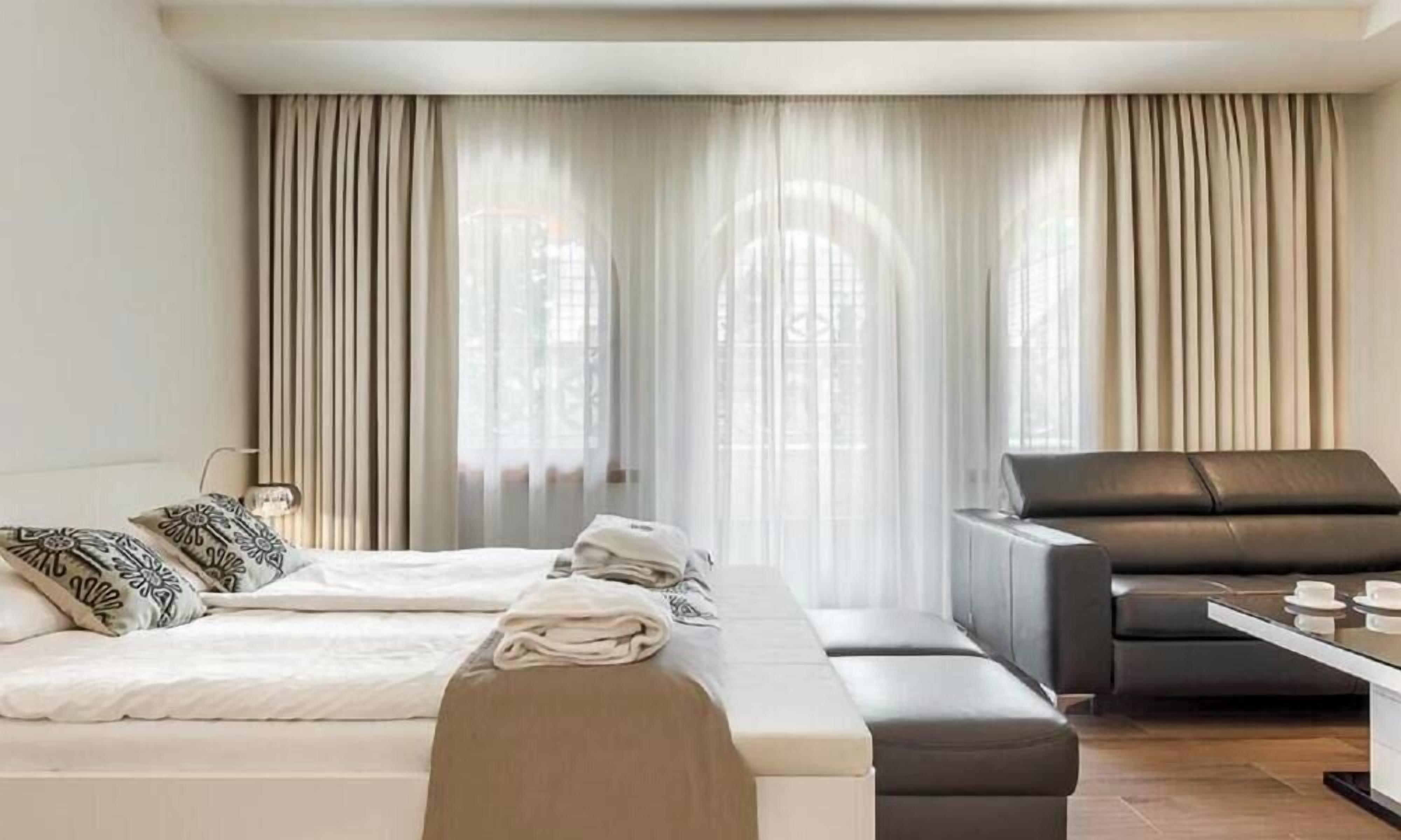 Ein Hotelzimmer mit Bett, einer Couch, einem kleinen Tisch und Vorhängen.