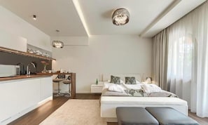 A modern bedroom with a large bed, bedside tables, a desk, and a chair.