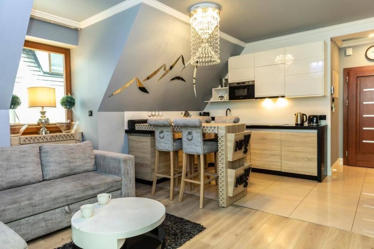 A modern kitchen with bar stools, a dining table, and a chandelier.