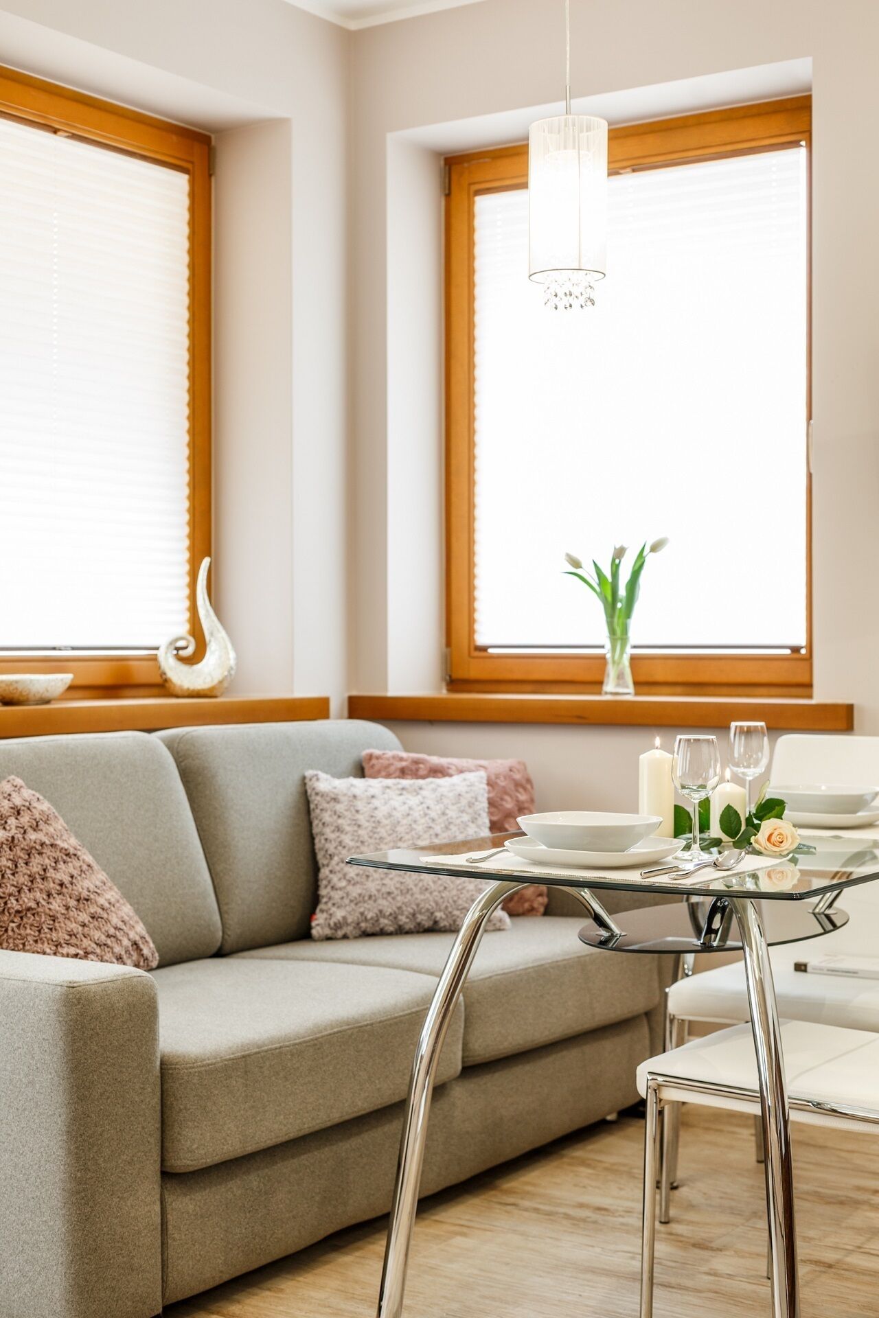 A modern living room with a sofa, dining table, chairs, and a chandelier.