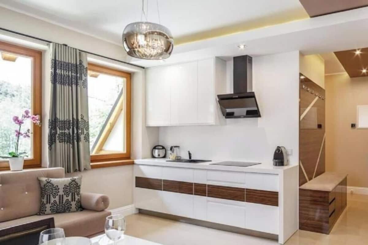 A modern kitchen with white cabinets, a black range hood, and a built-in island with a sink.
