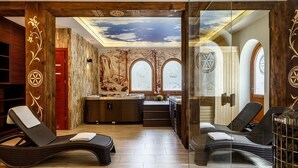 A spa room with two lounge chairs, a sauna, and a mural on the ceiling.