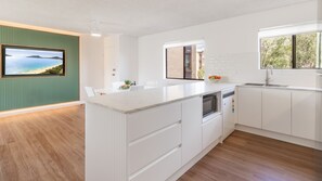 Una cucina moderna con una grande isola, mobili bianchi e vista sull'esterno attraverso una finestra.