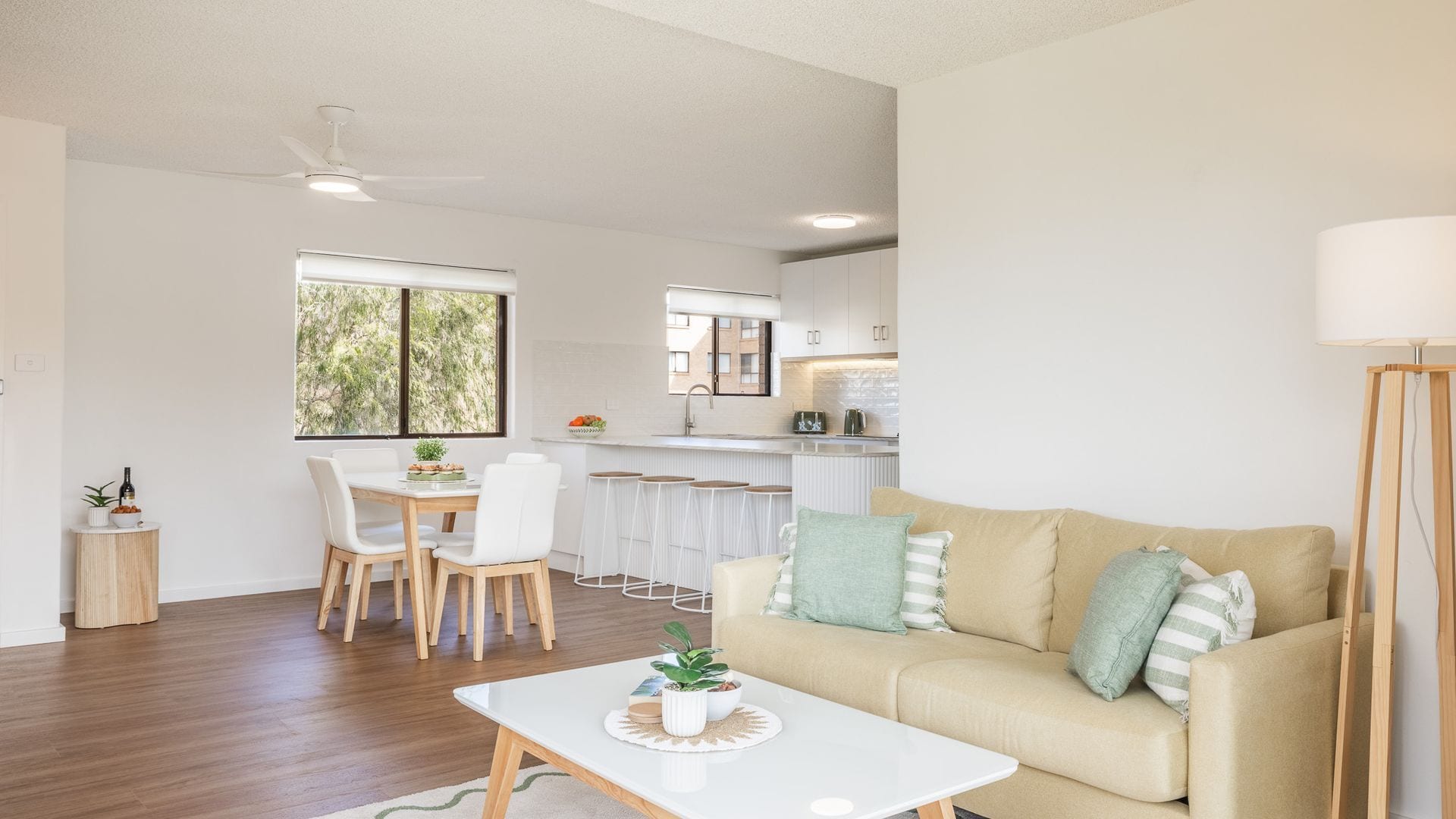 A modern living room with a sofa, a coffee table, and a dining area with chairs and a table.