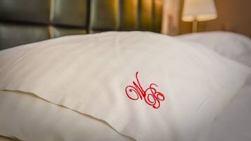 A bed with a white pillow featuring a red embroidered design.