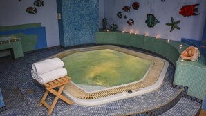 A hot tub with a wooden stool and towels, surrounded by mosaic tiles and fish decorations on the walls. - Willa Bryza (Gdynia)