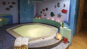 A spa room with a large bathtub, decorative fish wall art, and a bottle of champagne on the side. - Willa Bryza (Gdynia)