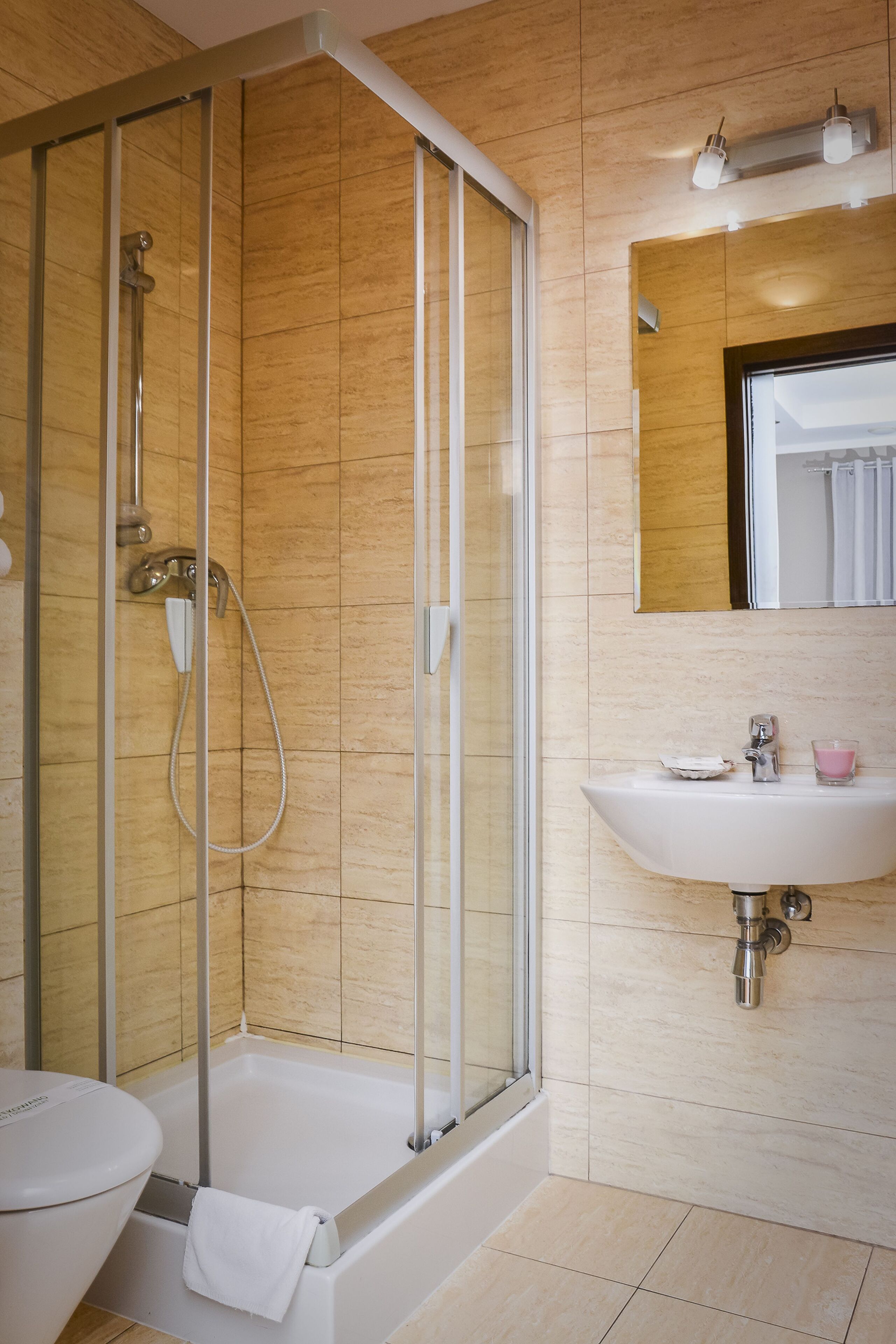 Un baño moderno con ducha envuelta en vidrio, un lavabo blanco y un espejo encima.
