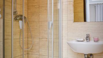Un baño moderno con ducha envuelta en vidrio, un lavabo blanco y un espejo encima.