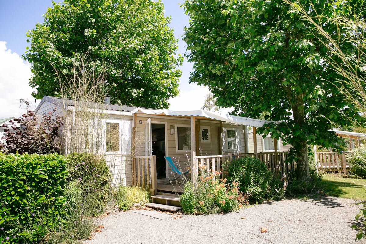 Une maison de plain-pied avec un porche à l’avant, un petit escalier menant à l’entrée et une clôture en bois entourant la propriété.