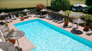 A rectangular swimming pool with clear blue water, surrounded by lounge chairs and potted plants. - Camping Saint Michel (Courtils)