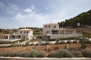 Una villa de piedra con piscina, jardín en terrazas y vistas del paisaje circundante.